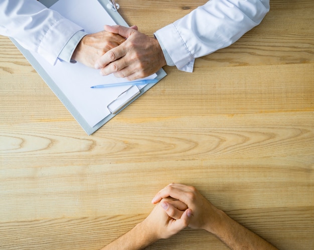 Hands of anonymous doctor and patient on table