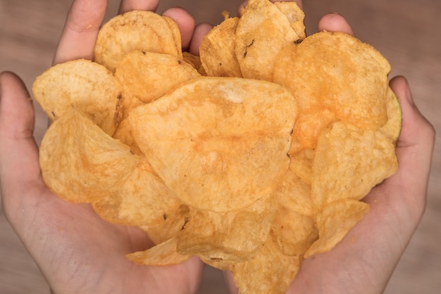 Hands are holding potato chips. Junk food made from cholesterol. Salty and crispy. Fast food snack.