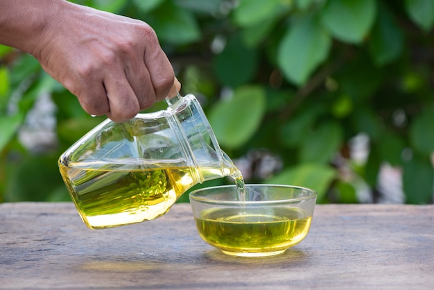 Hands are pouring olive oil into the jug