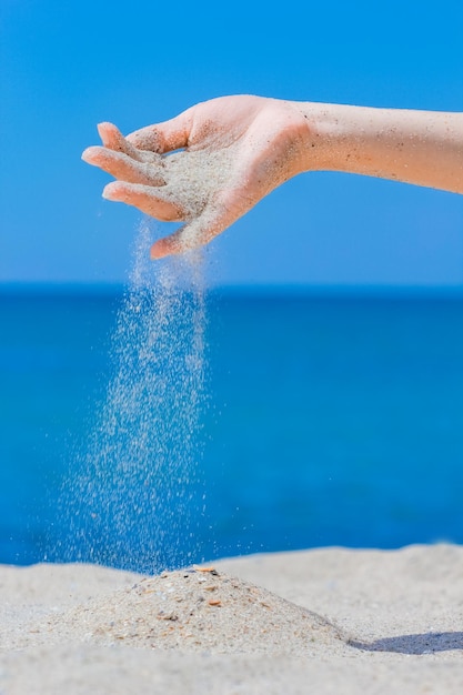 Hands are pouring sand by the sea