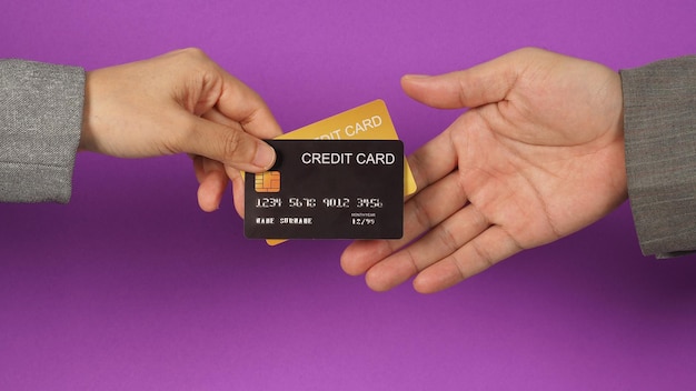 Hands are sent and receive black and gold credit cards on purple background