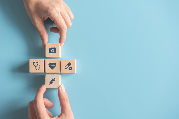 Hands arranging wood cube with medical symbol on pastel blue