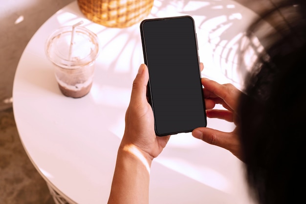 Hands of Asian man using smartphone in cafe