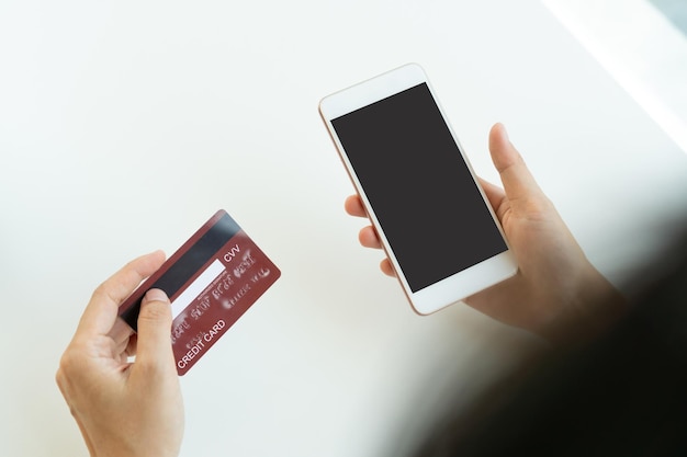 Hands of Asian woman show mobile phone with blank screen for copy space advertisement while holding credit card Close up Technology and lifestyle Cashless society concept