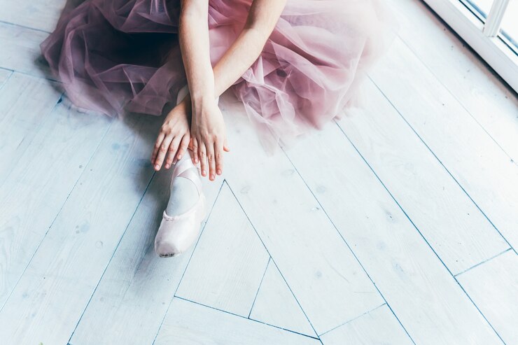 Photo 핑크 투투 스커트의 발레리나 손은 하얀 빛 홀의 다리에 포인트 슈즈를 착용합니다. 젊은 클래식 발레 댄서 소녀