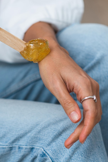 The hands of the beautician hold liquid sugar paste