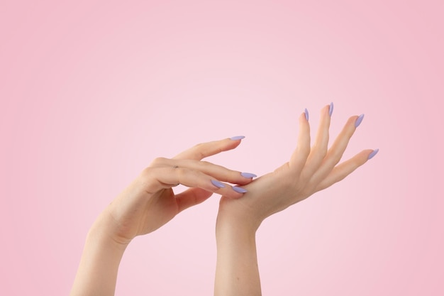 Hands of a beautiful well-groomed violet lavender nails gel polish on a pink background