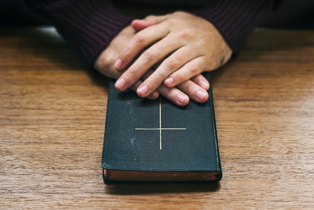 Hands over bible on wooden table