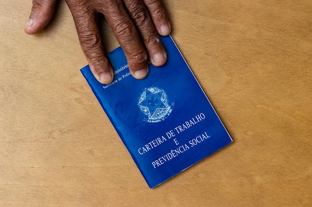 Hands of black senior man holding work book, Brazilian social security document