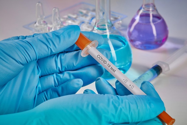 hands in blue disposable gloves holding testing kit medical flasks colorful chemical reagents ampoul