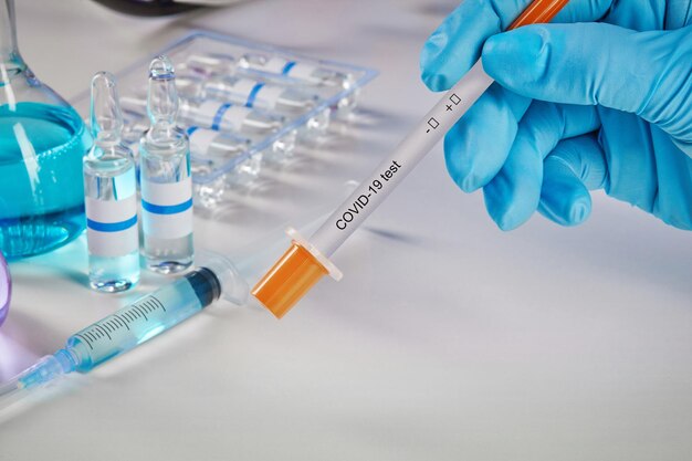 Hands in blue gloves holding testing kit medical flasks with colorful chemical reagents ampoules and