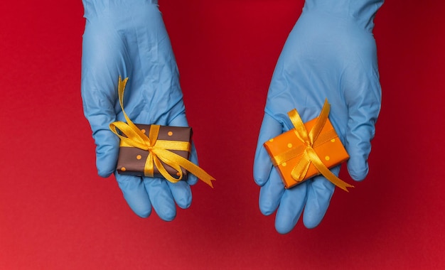 Hands in blue latex gloves holding gift boxes in color paper with polka dots with as a present