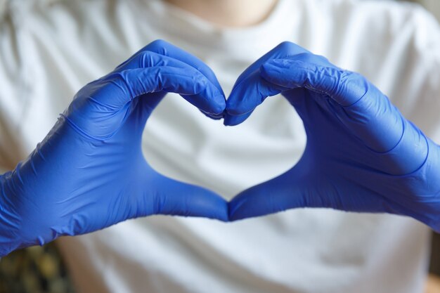 hands in blue medical gloves hold fingers in the shape of a heart. hand gesture.