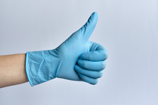 Photo hands in blue medical gloves on a white space shows a thumbs up like ..