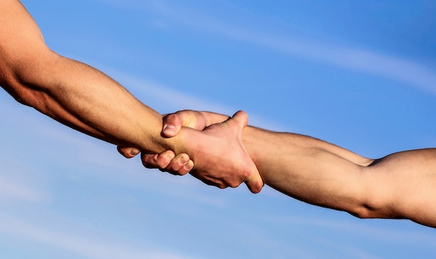 Hands of on blue sky background. Helping hand concept and international day of peace, support.