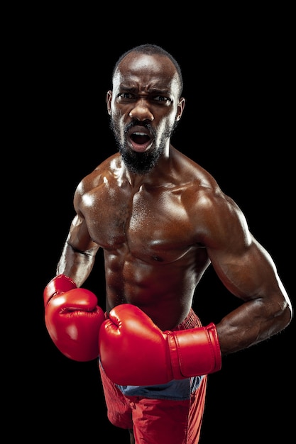 Photo hands of boxer over black background. strength, attack and motion concept. fit african american model in movement. afro muscular athlete in sport uniform. sporty man during boxing