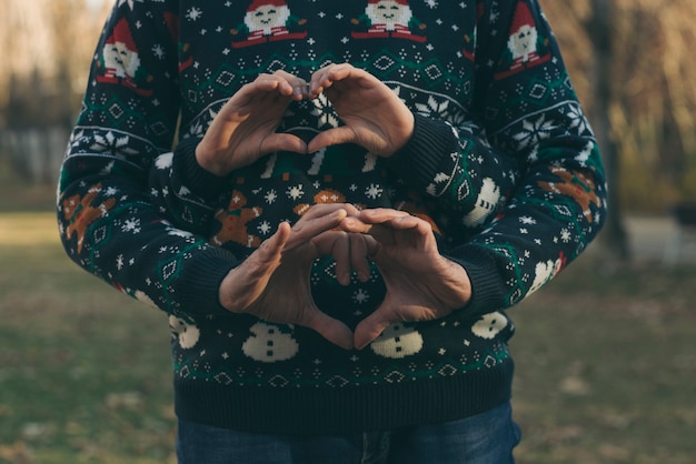 Mani del ragazzo e della ragazza con i vestiti di natale