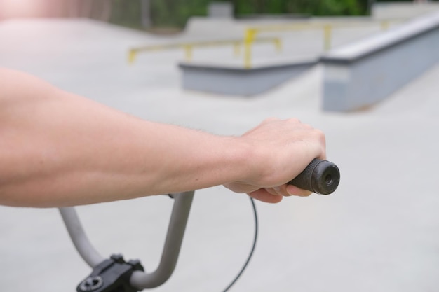 hands of boy on the handlebars of bmx bike man with bmx stands at concrete skate bmx park