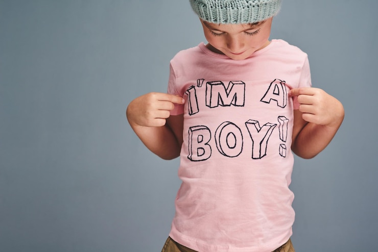 Photo hands boy and point at text on shirt for gender identity style and edgy fashion model by blue background child toddler and kid with pink clothes for choice learning and show print with promotion