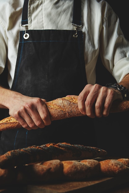 Hands breaking and separating fresh organic baguette