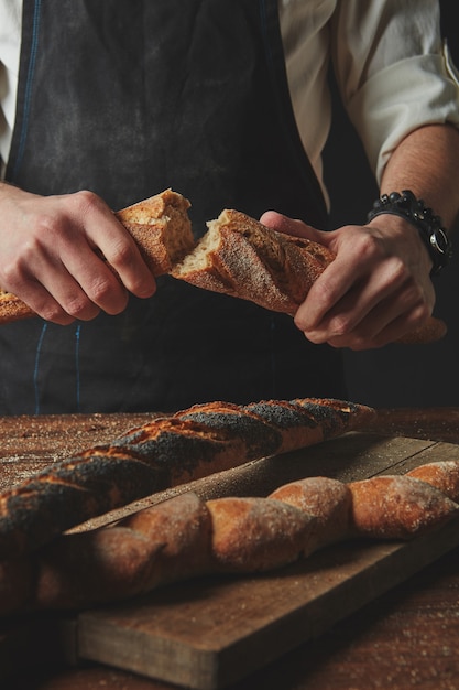 Hands breaking and separating fresh organic baguette