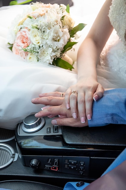 Hands of the bride and groom in the car at the wedding