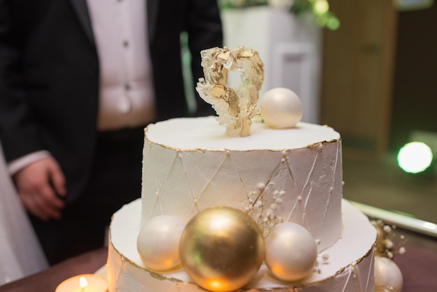 Hands of bride and groom cut of a slice of a wedding cake.