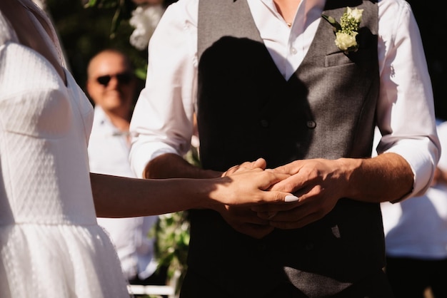 Hands of the bride and groom hold together on the wedding day