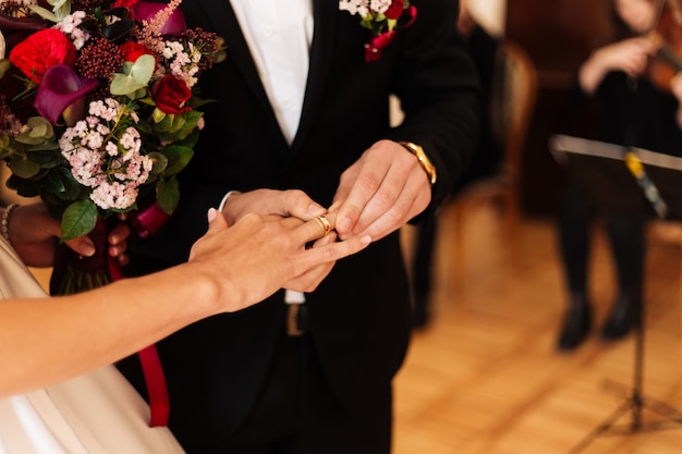 Hands of the bride and groom with bouquets closeup