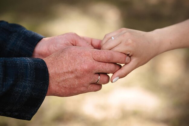 Foto le mani della sposa e dello sposo con anelli d'oro si tengono insieme il giorno del matrimonio