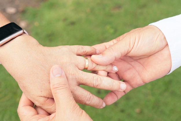 Hands of bride and groom with ring on finger Happy couple celebrating wedding outdoors