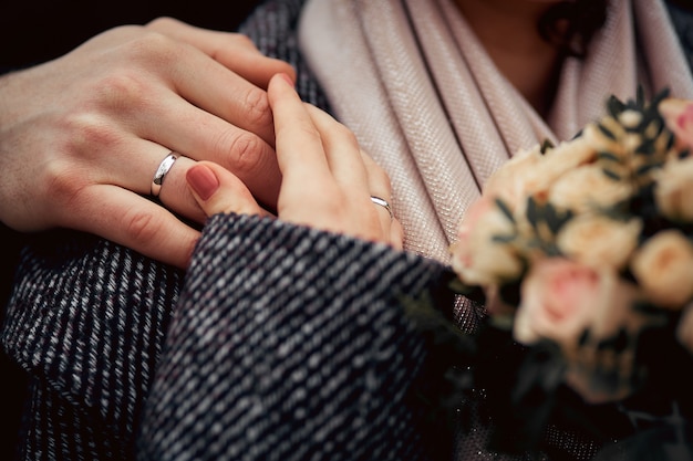 Photo hands of the bride and groom with wedding rings and bouquet