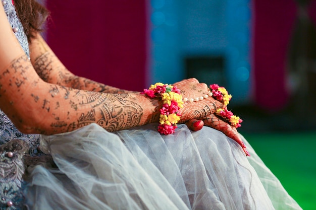 Le mani della sposa sono decorate splendidamente dall'arte indiana mehndi insieme a gioielli e braccialetti colorati