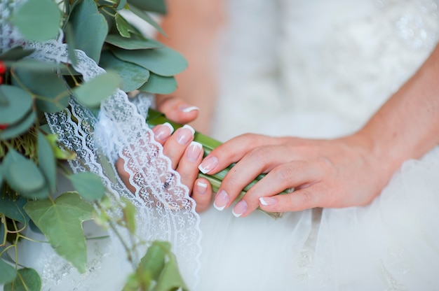 Hands of a bride, just married, a bridal bouquet is beside