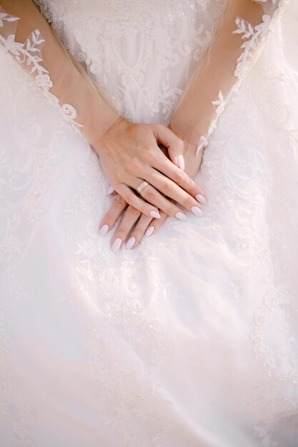 Hands of the bride in a white lace embroidered dress closeup