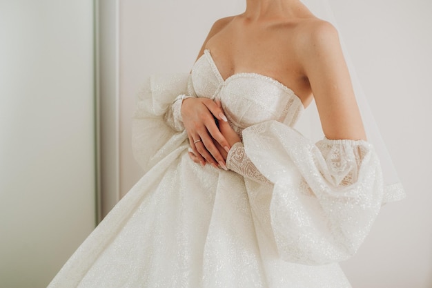 하얀 웨딩드레스를 입은 신부의 손에 다이아몬드 근접 촬영이 있는 금 약혼반지가 있습니다. 신부는 손가락으로 반지를 만집니다.