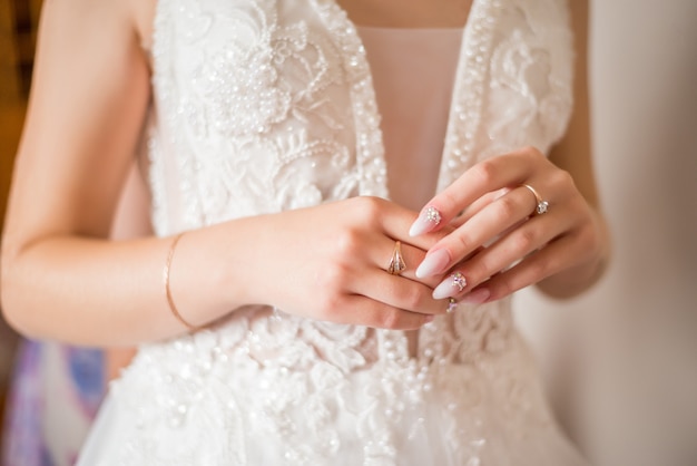 The hands of the bride with gold wedding ring with a diamond. Bride's Preparations. Wedding Morning. Jewelry. Manicure close up. Engagement. The buttonhole with flowers.