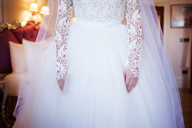 Hands bride with manicure. Wrist on the background of white lace dress covered with a veil