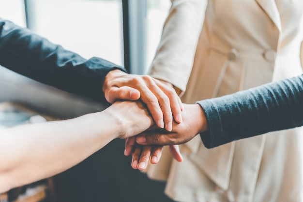 Hands of business people come together in a stack of hands to symbolize collaboration, teamwork to achieve goals and success.