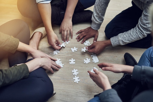 Foto mani di uomini d'affari e puzzle nella diversità del cerchio o nel lavoro di squadra per la soluzione di problemi o sopra il gioco pianificazione di gruppo e aiuto per la sinergia di supporto e il team building sul pavimento dell'ufficio