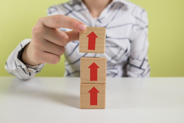 Hands of a business woman stack wooden blocks with an arrow up Ladder career path concept for successful business development The concept of financial percentage growth