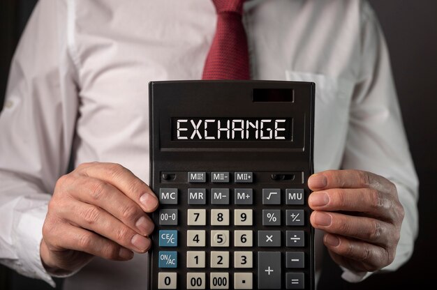 Hands of businessman with exchange word on calculator.