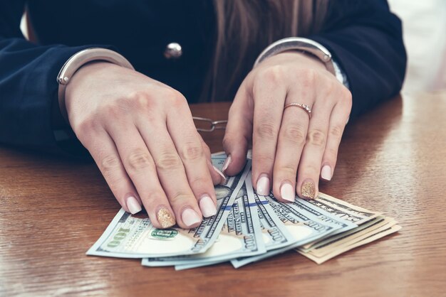 Hands of businesswoman in handcuffs with dollar notes