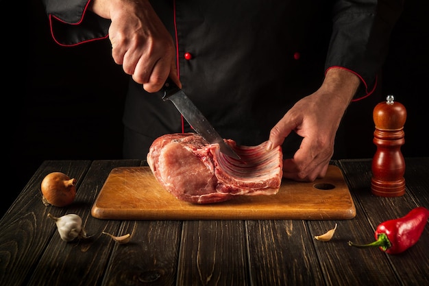 Hands of a butcher with a knife in the kitchen