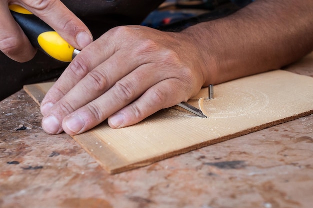 hands of cabinetmaker carving wood with gouge