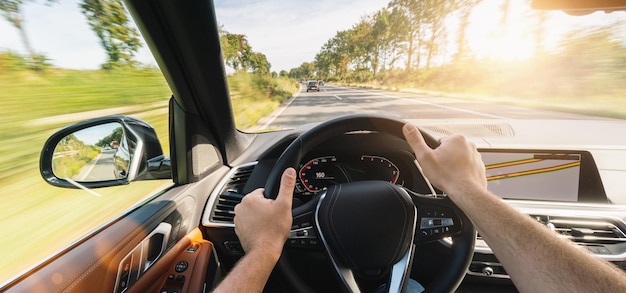 Hands of car driver on steering wheel road trip driving on highway road