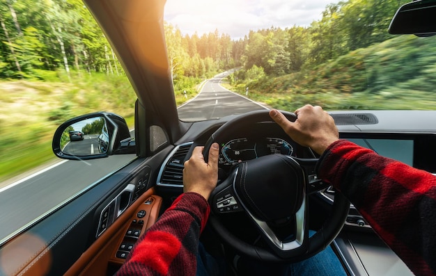 Hands of car driver on steering wheel road trip driving on highway road