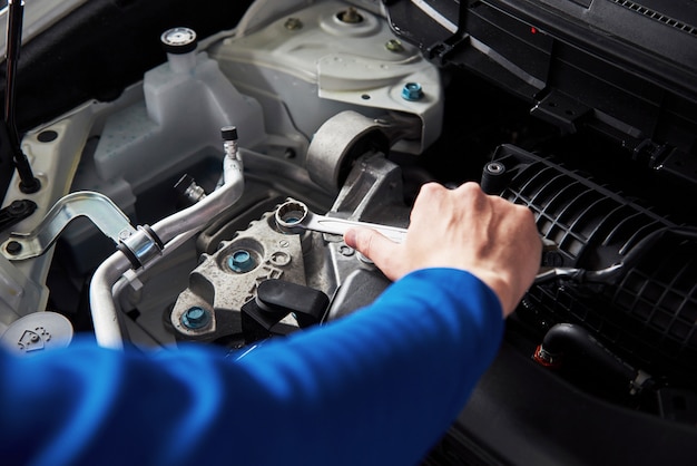 Hands of car mechanic with wrench in garage