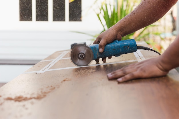 Mani di carpentiere che tagliano pezzo di legno con sega circolare elettrica