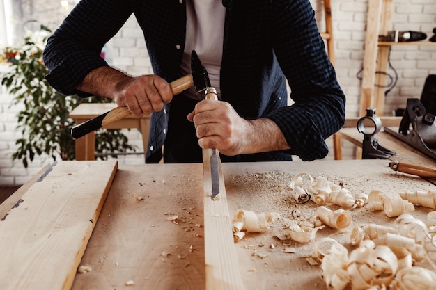 Hands of a carpenter working with chisel and hammer